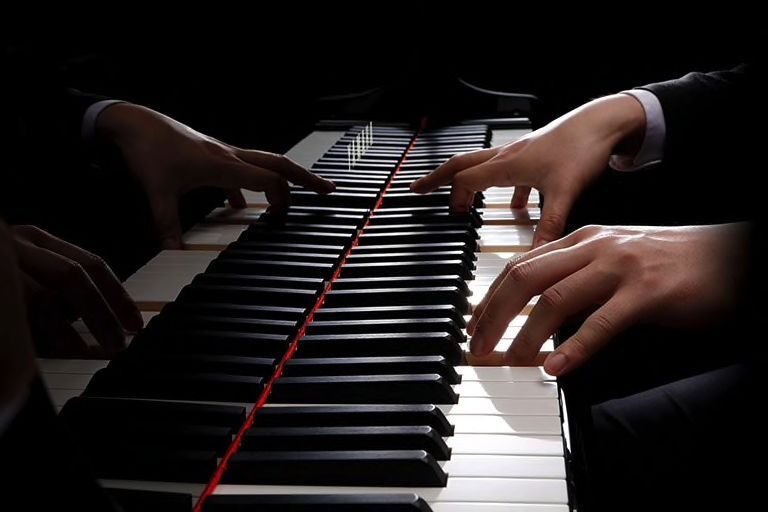 Gäste im Gespräch neben einem schwarzen Yamaha-Flügel